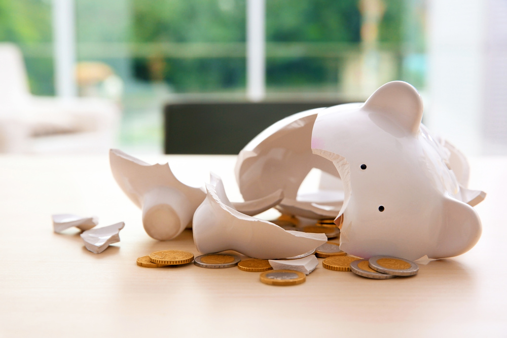 Broken piggy bank with coins on table indoors