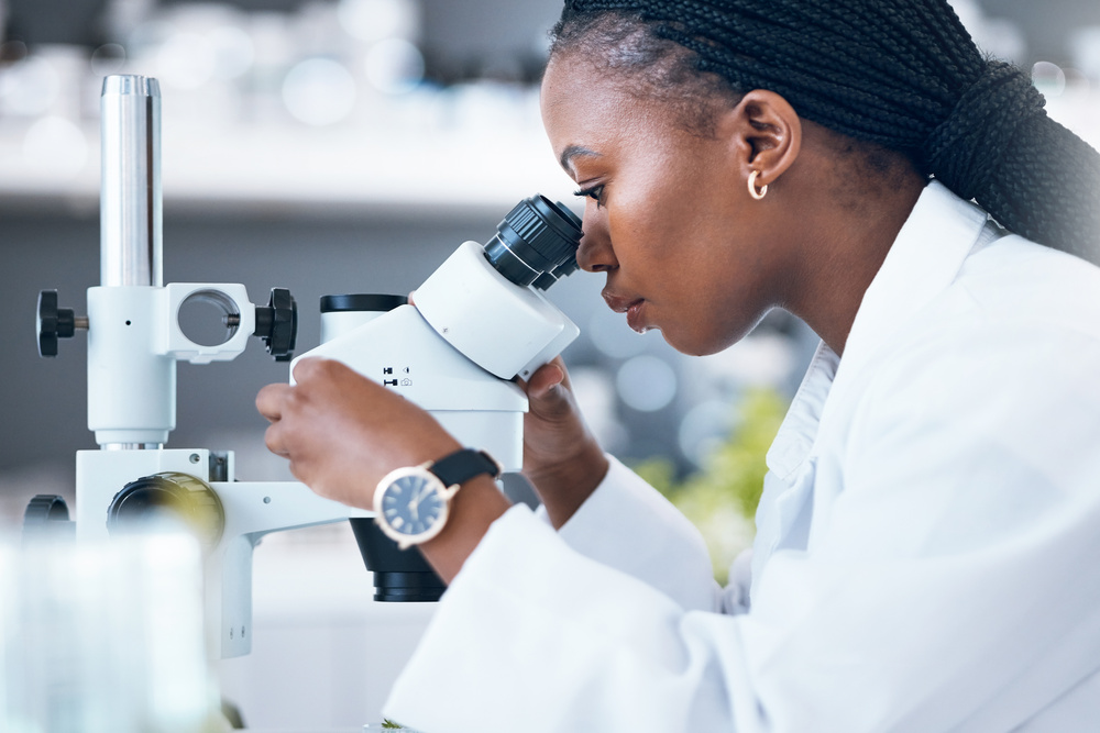 Microscope, black woman and medical science in laboratory for research, analytics and medicine. Woman, doctor and scientist study at work for an investigation, healthcare and futuristic or innovation.