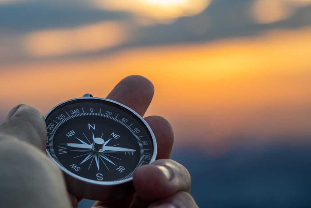 compass in hand with sunset sky on the background