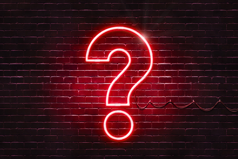 Neon sign on a brick wall in the shape of a question mark.(illus