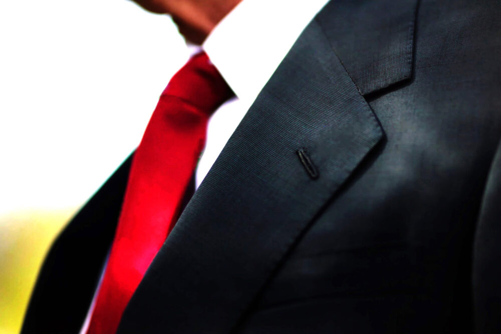 a black business suit jacket with white shirt and red tie, man n