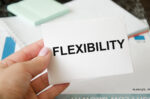 A woman's hand holding a card with the word FLEXIBILITY printed on it