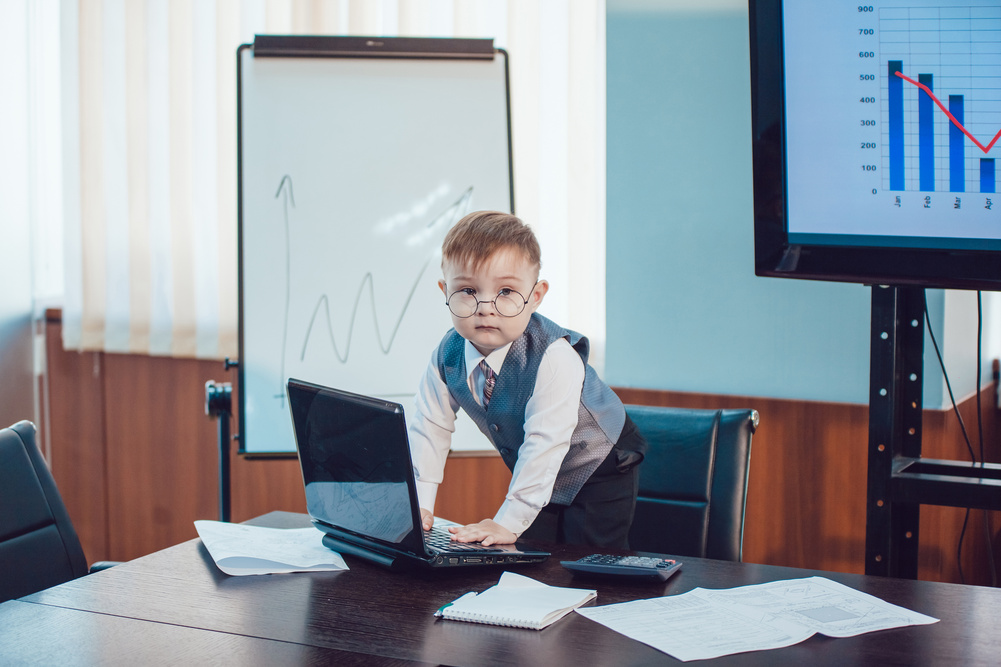 Children businessmen are meeting in the office sitting at the computer