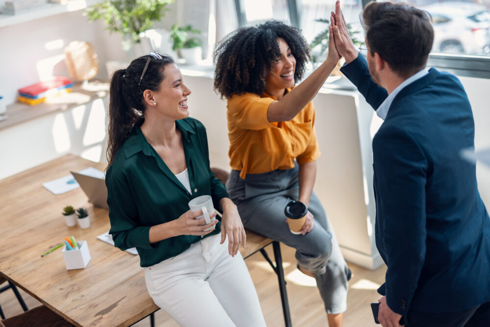 Shot of business team celebrating good job while holding up their right hands on modern startup