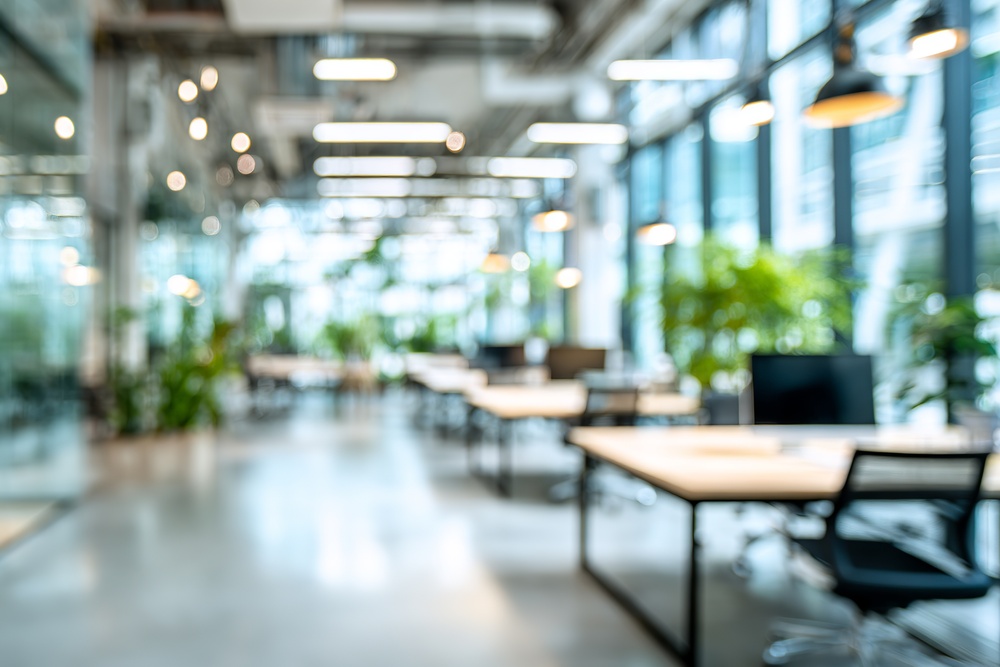 Abstract office space with natural light flooding through large windows and lush greenery creating a modern workspace environment.