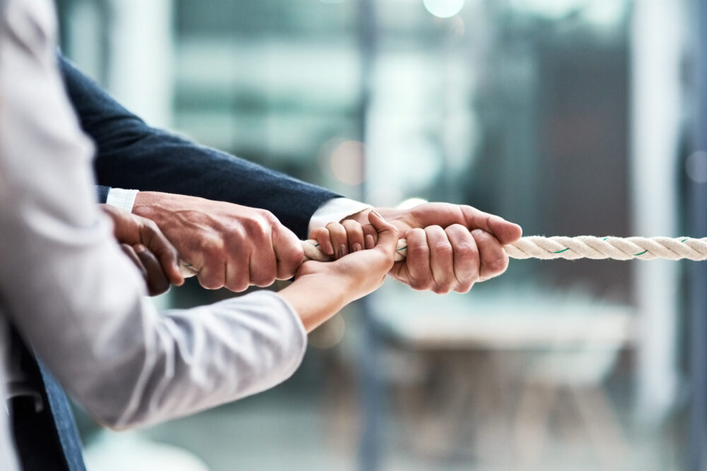 Hands, teamwork and rope with business people grabbing during a game of tug of war in the office. Collaboration, help or strength with a team of employees or colleagues pulling an opportunity at work.