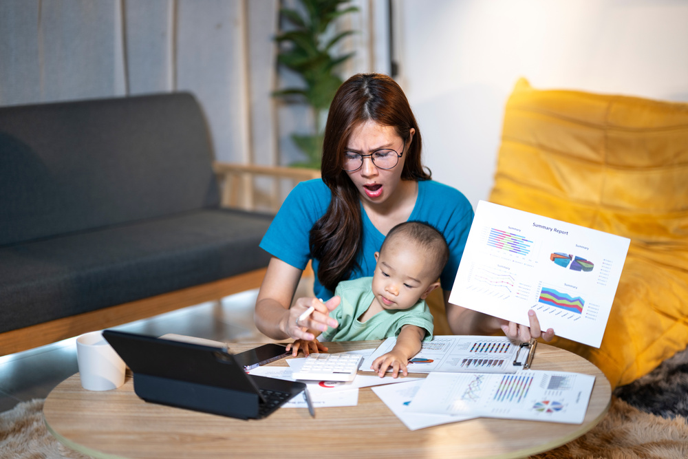 Working mother multitasking from home with her baby on a difficult work day