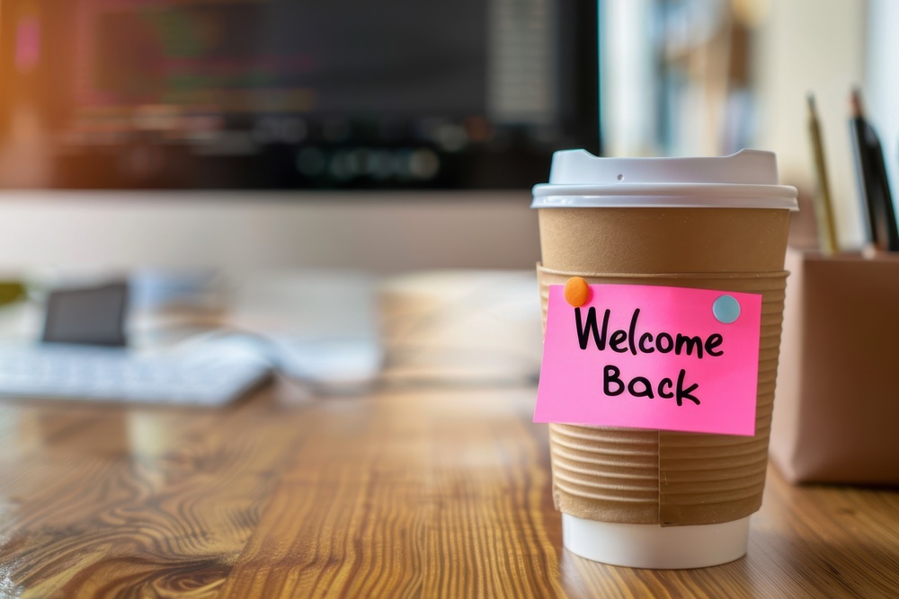 Coffee cup in a workplace setting with a “Welcome Back” sticker symbolising support for employees returning from parental leave