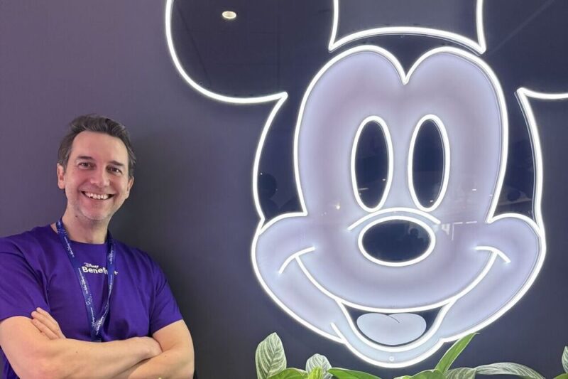 Striking LinkedIn photo of Max Landry, co-founder, Euphoric, in front of a back-lit image of Mickey Mouse, adding a playful touch to his new client-win announcement on LinkedIn