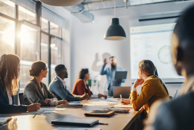 Business leaders reviewing workplace wellbeing strategy with data dashboards, collaboration and employee engagement insights visible
