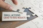 Close-up of a hand placing a puzzle piece reading “small actions lead to big results”, symbolising workplace mental health improvements through everyday action