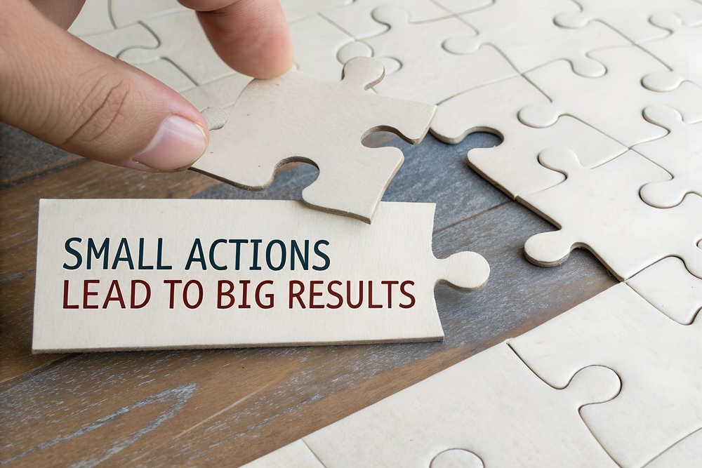 Close-up of a hand placing a puzzle piece reading “small actions lead to big results”, symbolising workplace mental health improvements through everyday action