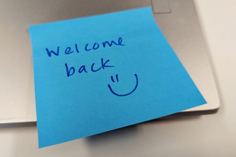 Handwritten “Welcome back” note attached to a laptop, representing workplace support and reassurance for employees returning after mental health absence.
