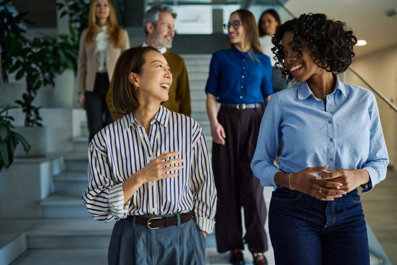 Diverse group of employees walking and talking together in a modern office workplace.