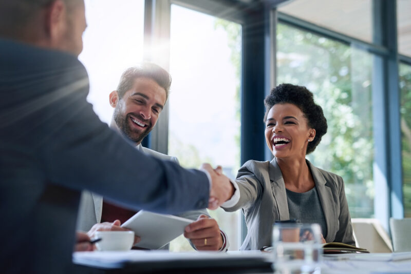 Diverse business professionals shaking hands to agree the purchase of digital workplace wellbeing and HR technology solutions, representing prevention, AI and personalised employee support