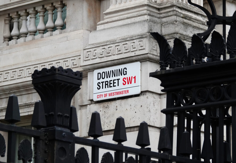 Close-up of the Downing Street street sign in London, symbolising UK political uncertainty and its potential implications for workplace health, wellbeing and employment policy.