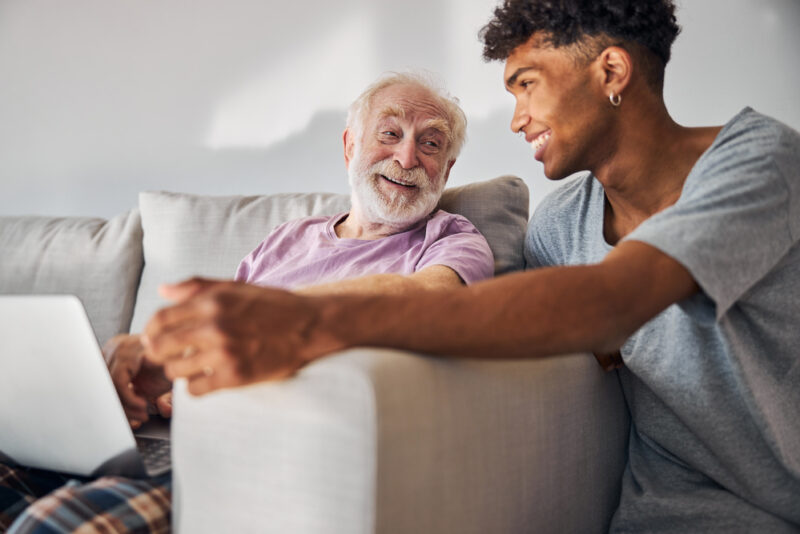 A young man supporting his grandfather at home, representing the millions of unpaid carers balancing caring responsibilities alongside work
