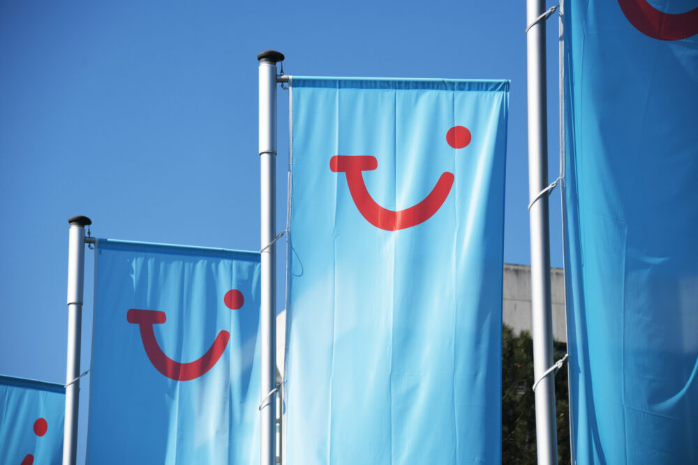 TUI logo displayed on branded flags outside a holiday venue, representing the company's commitment to building a neuro-inclusive workplace and customer experience.