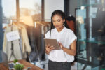 Cropped shot of a young business owner using her tablet while standing in her store.