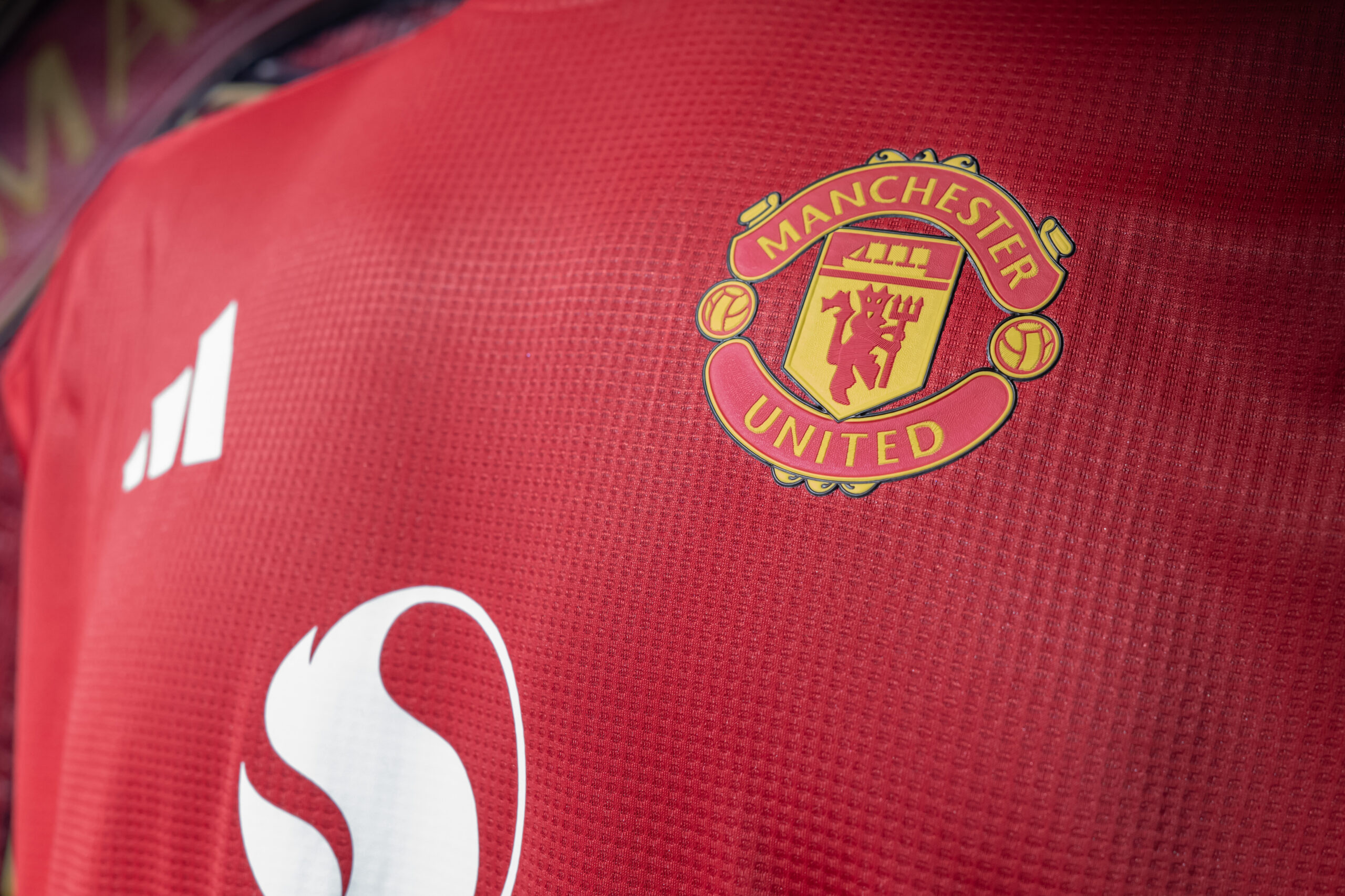 Manchester United FC logo displayed on a red football shirt, illustrating the club's new partnership focused on mindset, performance and organisational culture development