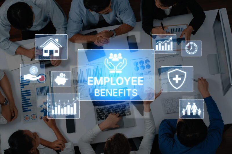 Collaborative Office Environment with Diverse Professionals Discussing Employee Benefits and Analyzing Data for Workforce Improvement