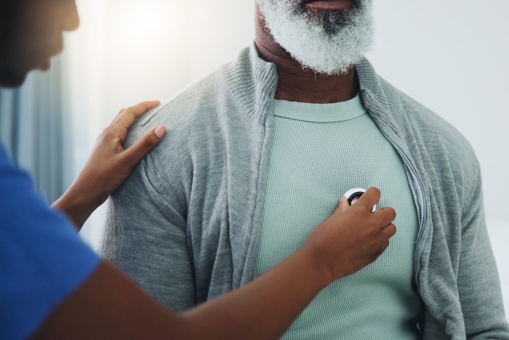 Nurse using a stethoscope to examine a man's chest during a health check.