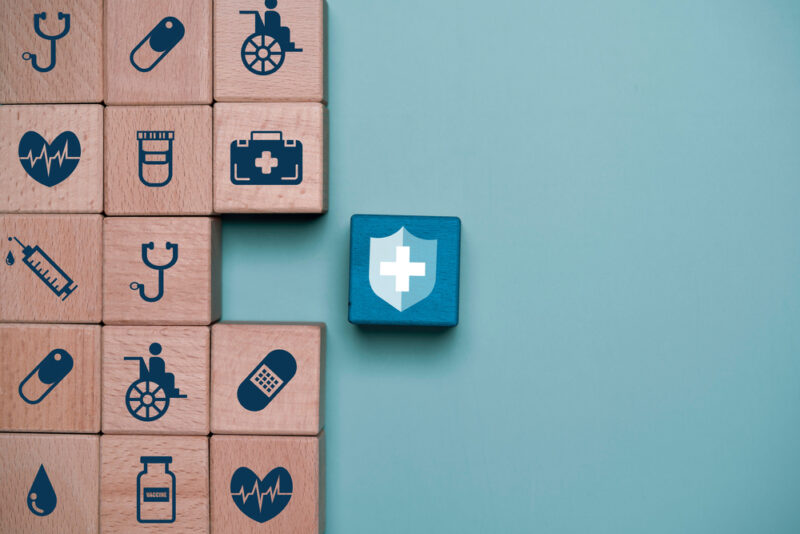 Wooden blocks, each with different health-related symbols showing the need for an interconnected approach to workforce health