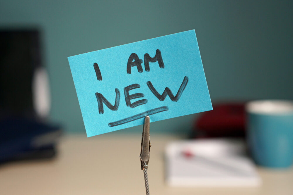 Post it note on a desk with "I am new" written on it