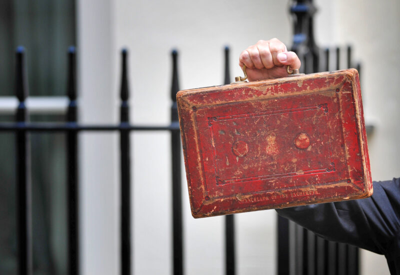 The Chancellor of the Exchequer holding the red Budget briefcase outside 10 Downing Street in Whitehall.