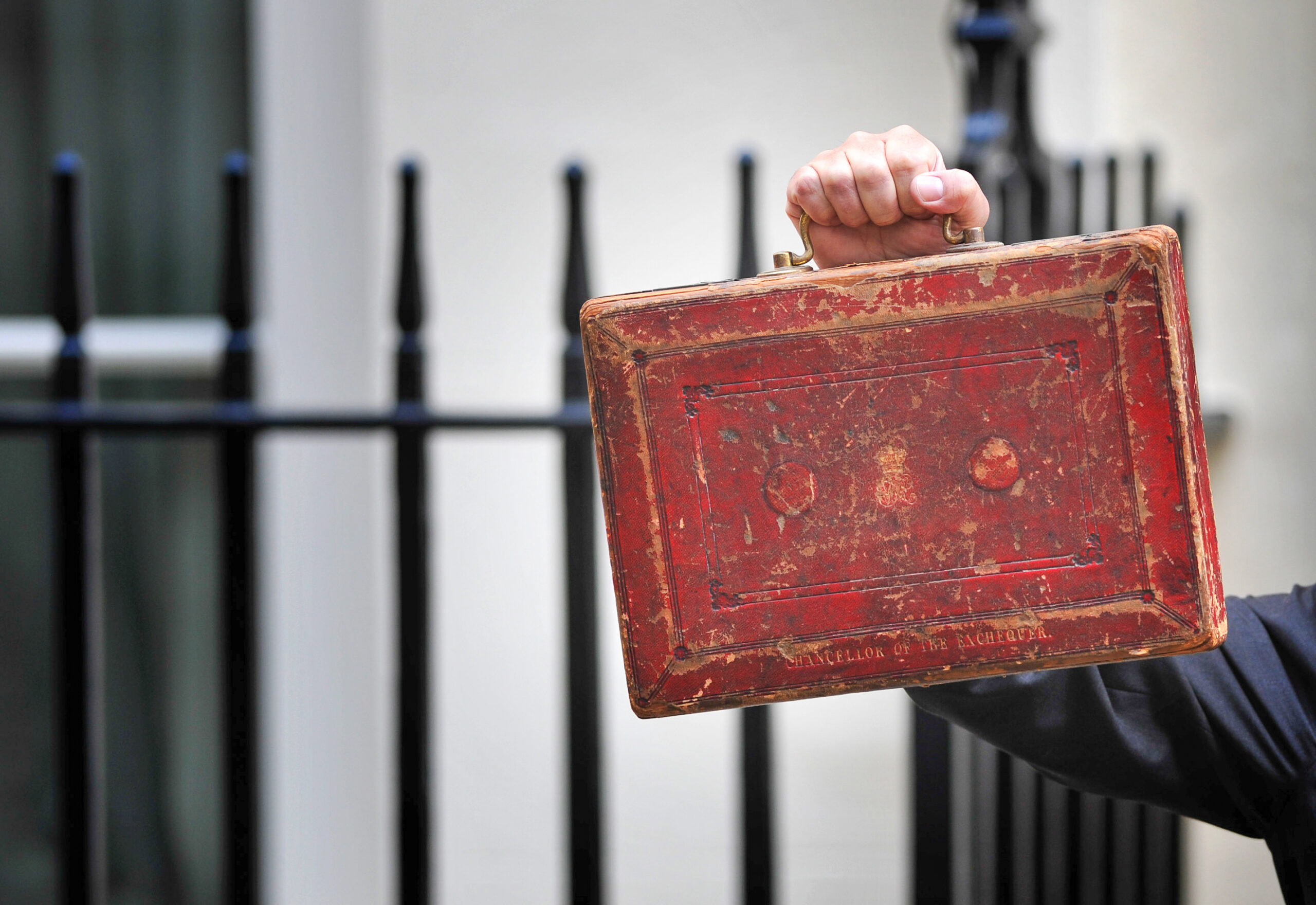 The Chancellor of the Exchequer holding the red Budget briefcase outside 10 Downing Street in Whitehall.